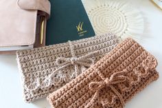 three crocheted purses sitting on top of a table next to a passport