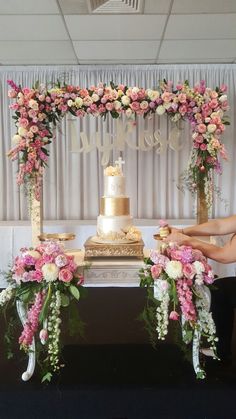 two people sitting at a table with a cake and flowers