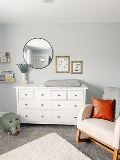 a baby's room with a white dresser and mirror