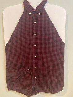 a red and black checkered shirt hanging on a white wall next to a pair of scissors