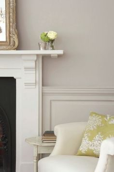 a white chair sitting next to a fireplace with a mirror on it's wall