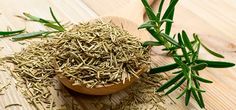 a wooden spoon filled with rosemary on top of a table