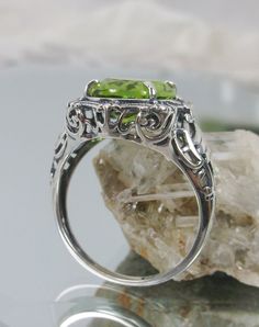 "Natural Green Peridot Ring Description Beauty Design#229 MADE To ORDER This is a brand new stunning Art Nouveau/Victorian reproduction sterling silver filigree ring. The oval-cut high-quality natural peridot is 12mm by 10mm (just shy of 3/8\" inch) in dimension... The ring is 5/8th of an inch (16.5mm) NS (long) on the finger. The ring and gem sit 7mm off the finger. The inside of the band is marked 925 for sterling. Notice the beautiful filigree swirl like the craftsmanship of the silver settin Unique Luxury Peridot Rings, Art Deco Oval Jewelry With Halo Setting, Classic Peridot Jewelry With Halo Setting, Art Deco Oval Filigree Ring With Gemstone, Round Peridot Jewelry With Halo Setting, Heirloom Green Oval Halo Ring, Oval Gemstone Filigree Ring In Art Deco Style, Oval Peridot Ring In White Gold, Green Rings With Intricate Design