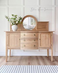 a wooden dresser with a mirror and potted plant