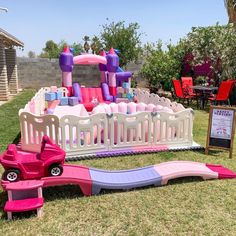 there is a pink and purple toy car next to a play set in the grass