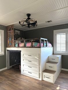 a loft bed sitting on top of a hard wood floor next to a white dresser