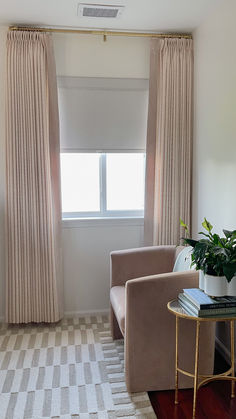 a living room with two chairs and a table in front of a window that has curtains