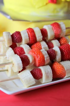 strawberries and bananas are arranged on skewers to be eaten at a party