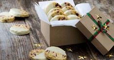 a box filled with cookies sitting on top of a wooden table next to a present