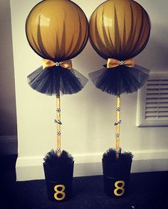 two black vases with gold numbers and tulle skirts, one has a bow on it