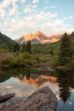 the mountains are reflected in the still water of this stream, which is surrounded by trees and rocks