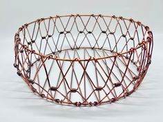 a wire basket is shown on a white surface with small beads in the bottom and sides