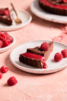 chocolate cake with raspberry toppings on white plates