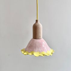 a pink and yellow light hanging from a ceiling fixture with a white wall in the background