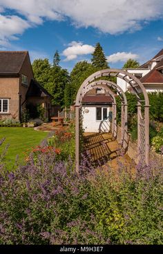 a garden with flowers and an arch in the middle, surrounded by houses - stock photo