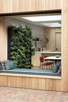 an open window with plants on the wall and chairs in the back ground, behind which is a kitchen