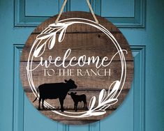 a wooden sign that says welcome to the ranch with a cow and calf on it