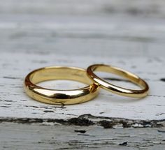 two gold wedding rings sitting on top of each other