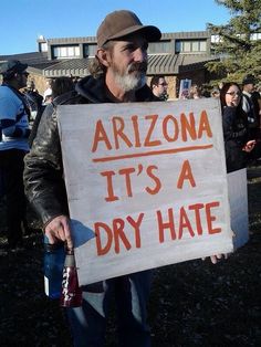 a man holding a sign that says arizona it's a dry hate