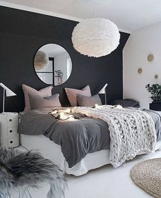 a bedroom with black and white walls, grey bedding, gray rugs and round mirror on the wall