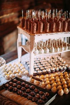 an assortment of cupcakes and pastries on display in front of a wooden table