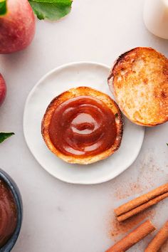 two pieces of bread on a white plate with cinnamon sticks and apples in the background