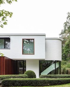 a white house surrounded by hedges and trees