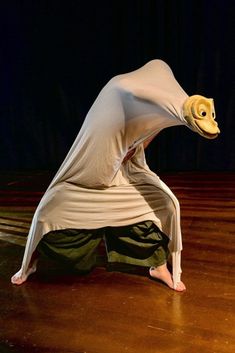 a woman in white shirt and green pants doing a handstand on wooden floor