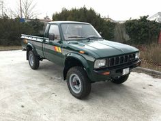 a green pick up truck is parked on the street