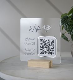 a glass plaque with a qr code on it next to a potted plant