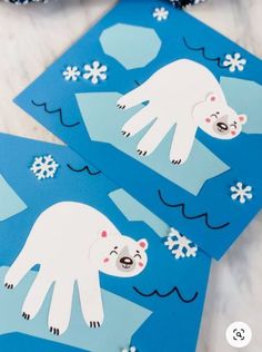 two polar bears cut out from paper with snowflakes on the ground behind them