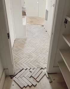 an open door leading into a room with white walls and floor tiles on the ground