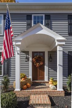 an american flag is hanging on the front door of a house with pumpkins and gourds