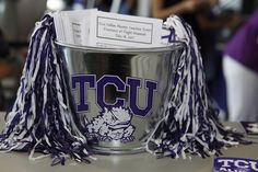 a silver cup with purple and white tassels on it sitting on a table