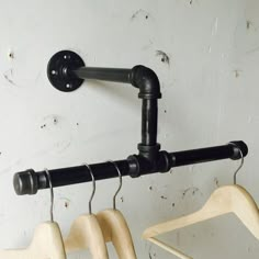 three wooden hangers are hanging on the wall next to each other, with two black handles and one white hanger