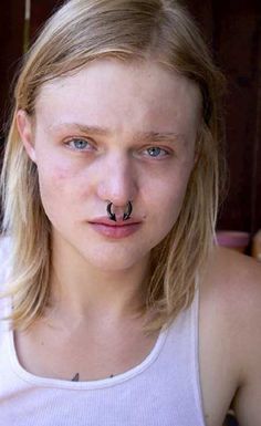 a woman with a nose ring and piercing on her nose is staring at the camera