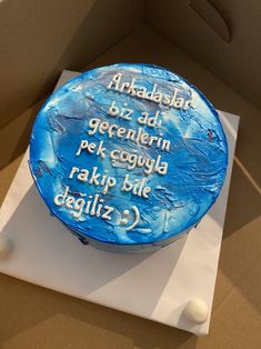 a blue cake sitting on top of a cardboard box with words written in white frosting