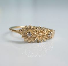 This dainty daisy ring is a beautiful little stacking ring that is like a little bouquet of gold flowers and diamonds wrapped around your fingers. This ring is made in solid 14 karat gold with and set with two genuine VS-SI white diamonds. Gentle Daisies embody many meanings, from joy to good luck and new beginnings. In Victorian times, they were taken to represent loyalty and trust. Innocent daisies are a simple flower with many meanings, and are a perfect daily ring companion, sure to make you Gold Daisy Ring, Delicate Gold Flower Stackable Rings, Dainty Cluster Promise Ring, Delicate Stackable Yellow Gold Flower Ring, Dainty Gold Flower Stackable Rings, Dainty Flower Ring With Rose Cut Diamonds For Anniversary, Dainty Cluster Ring For Anniversary, Delicate Yellow Gold Stackable Flower Ring, Dainty Rose Cut Diamond Flower Ring For Anniversary