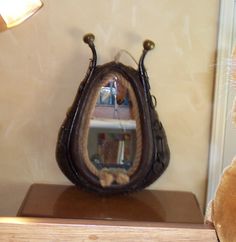 a teddy bear sitting next to a mirror on top of a wooden shelf in front of a lamp