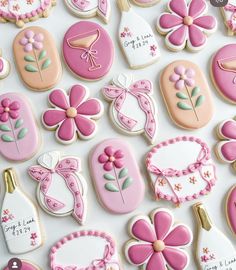 many decorated cookies are displayed on a white surface with pink and gold trimmings