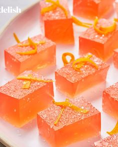 small square pieces of orange colored food on a white plate with yellow ribbon around the edges