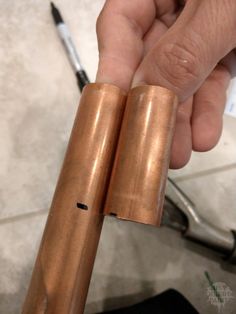 a person holding two copper tubes in their hand