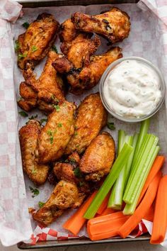 chicken wings, celery sticks and carrots on a tray with ranch dressing