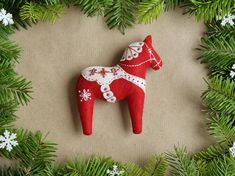 a red horse ornament sitting on top of a green christmas tree filled with snowflakes