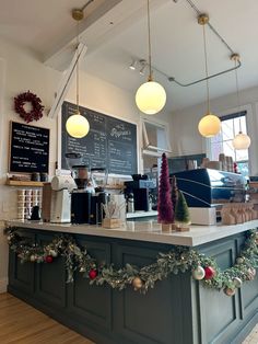 a coffee shop decorated for christmas with garland on the counter and lights hanging from the ceiling