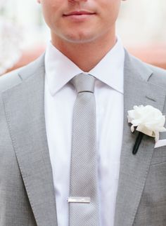 a close up of a person wearing a suit and tie with a flower in his lapel