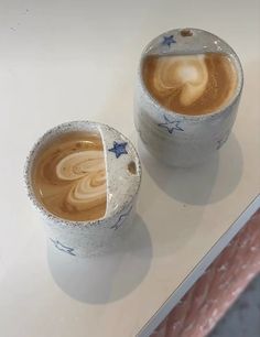 two cups with liquid in them sitting on a white counter top next to each other