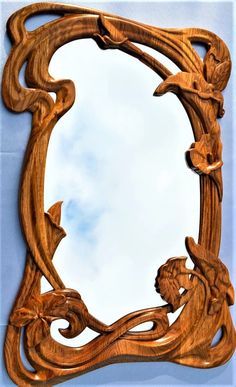 an ornate wooden mirror frame with carved wood carvings on the edges and sides, set against a blue sky background