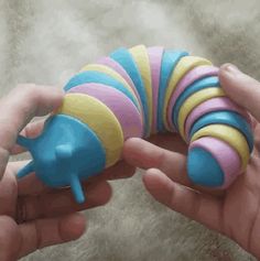 two hands are holding a toy in the shape of a caterpillar, and another hand is reaching for it