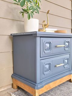 a blue dresser sitting on top of a rug next to a potted plant